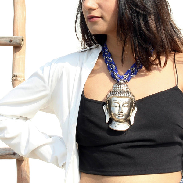 Silver buddha neckpiece with blue and silver string worn by a woman