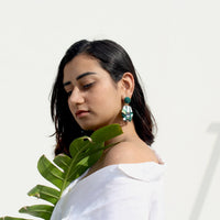 Turquoise earrings in hexagon shape worn by a woman